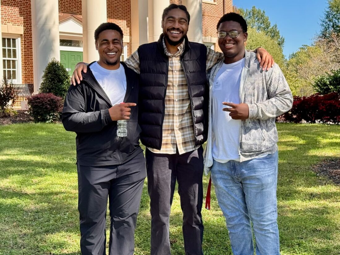 Three smiling men on a college campus
